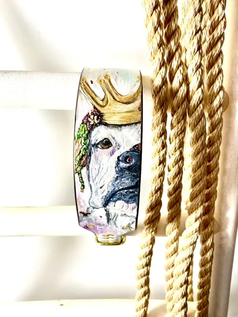 Helles Halsband mit Hundeportrait und goldener Krone, daneben ein Tauseil